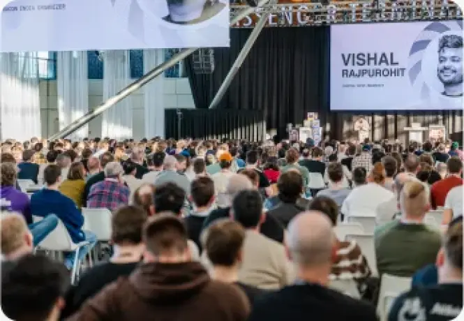 A conference screen displaying Vishal Rajpurohit's name to a seated crowd